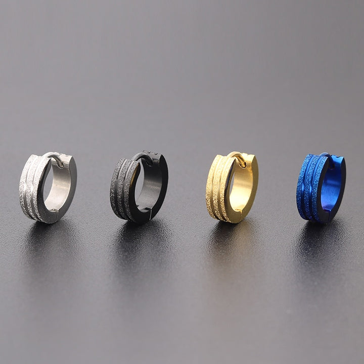 Une paire de boucles d'oreille anneaux homme en acier inoxydable, argent, plaqué or, noir et bleu. Conception audacieuse avec trois anneaux pailletés et deux fins anneaux métallisés. Dimensions : 9 x 4 mm. Poids : 3,6 g. Style contemporain et raffiné.