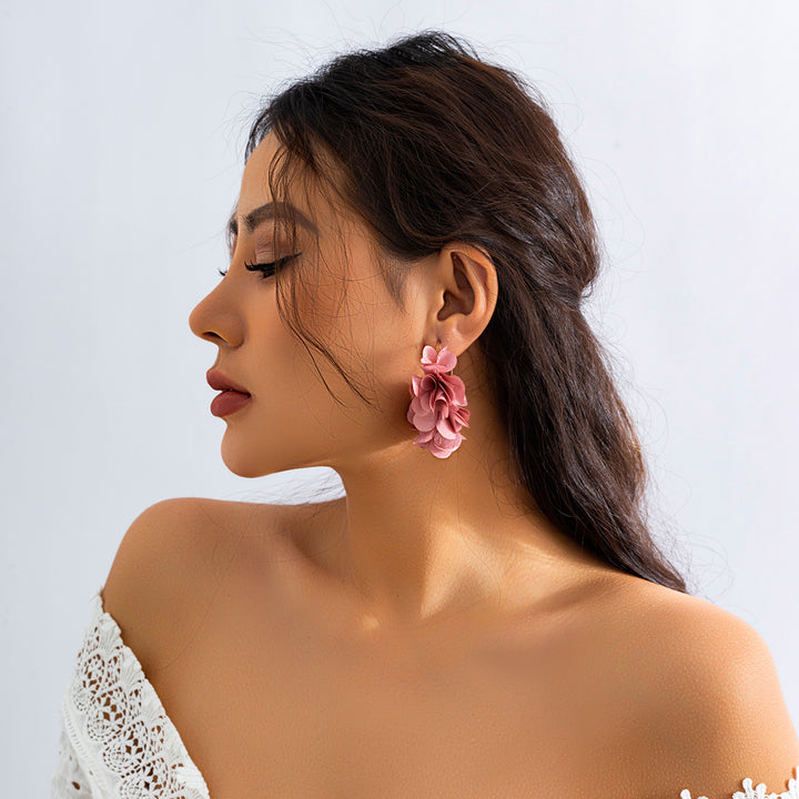 Une femme aux yeux fermés portant une robe blanche et des boucles d'oreille en fleurs en tissu - Boucle d'oreille créole fine dorée fleurs pendantes tissu - Femme. Ajoutez une touche florale à votre tenue avec ces boucles d'oreille délicates et élégantes. Légères et féminines, elles sont parfaites pour les amoureuses de la nature et de la mode.