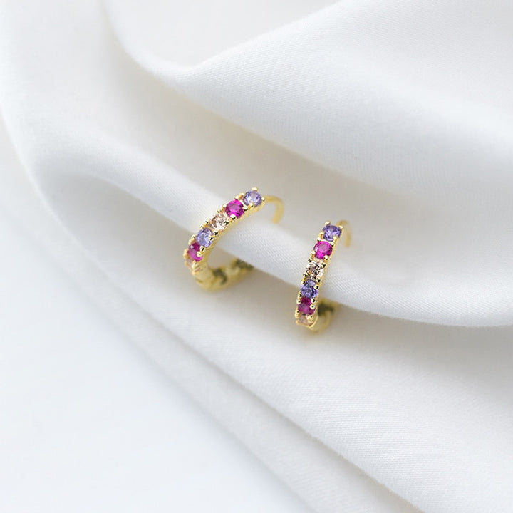 Une paire de boucles d'oreille créoles en argent 925 avec des strass colorés - Femme - Argent 925. Des pierres roses, violettes et jaunes ornent ces boucles d'oreille pour un éclat multicolore. Dimensions : 1,4 x 0,2 cm.