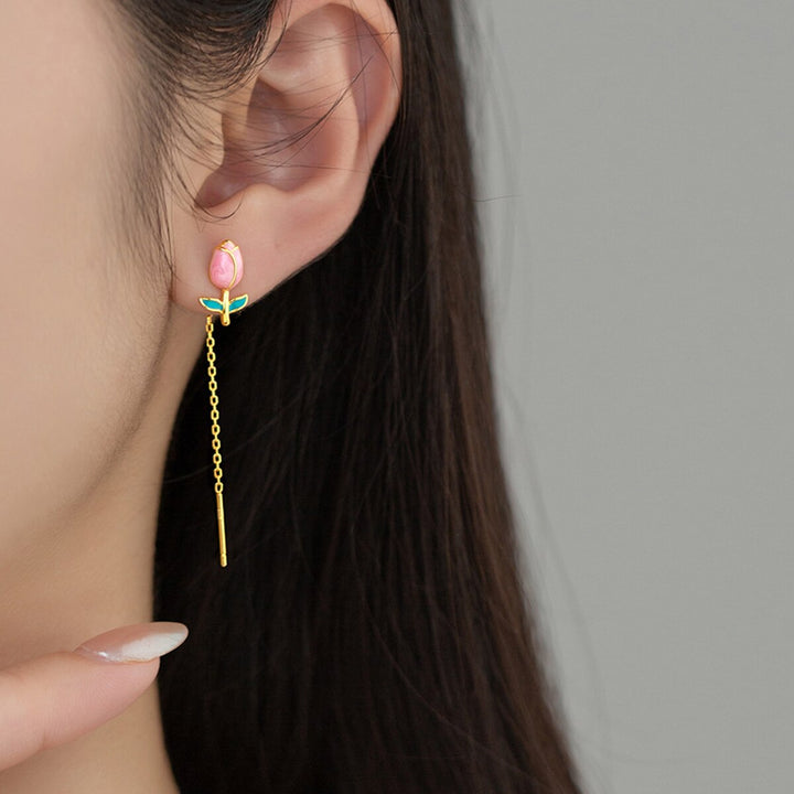 Une femme porte une boucle d'oreille en forme de tulipe colorée avec une chaîne pendante en argent 925.
