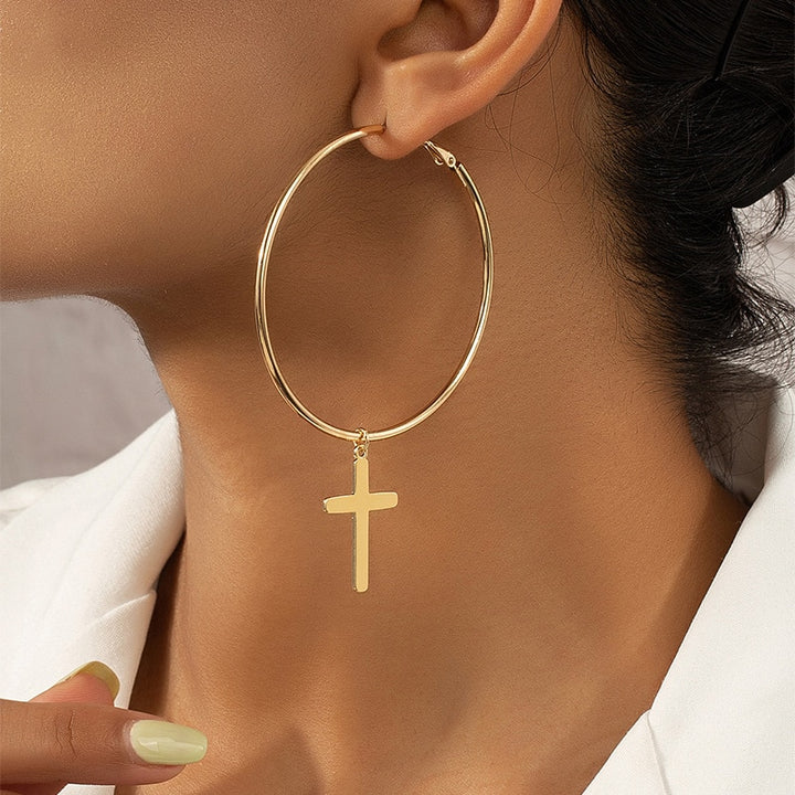 Boucle d'oreille créole avec croix pendante en or pour femme. Élégante et raffinée, cette boucle d'oreille apporte une touche d'élégance intemporelle à votre tenue.