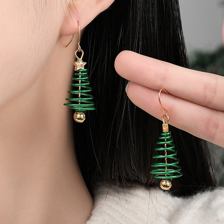 Une personne portant des boucles d'oreille pendantes en forme de sapin de Noël en spirale verte avec une étoile dorée - Femme.